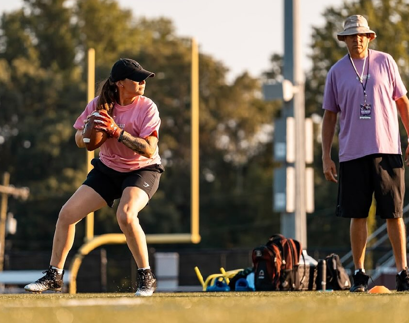 Girls flag quarterback in a ready stance with a coach watching