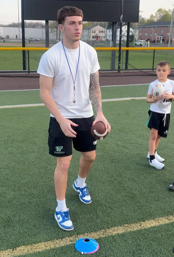 Coach Daron Bryden working with a young quarterback on the field