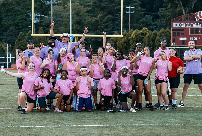 Girls flag football players and coaches together on the field